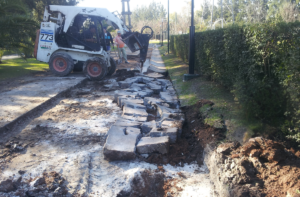 Obras bobocat rompiendo calle en mal estado para una obra de mantenimiento vial y repavimentación